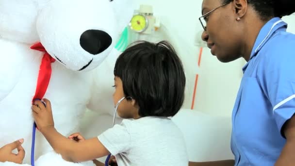 Niño paciente jugando con estetoscopio y osito de peluche — Vídeos de Stock