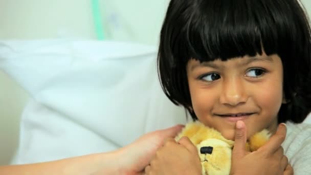 Girl hugging teddy bear in hospital bed — Stock Video