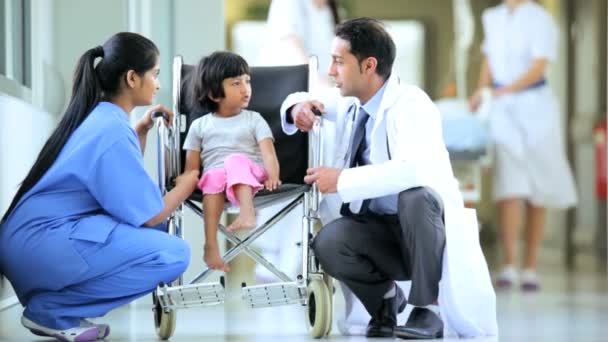 Asiatiska indiska sjuksköterska barnläkare lilla etniska flicka sjukhus rullstol — Stockvideo