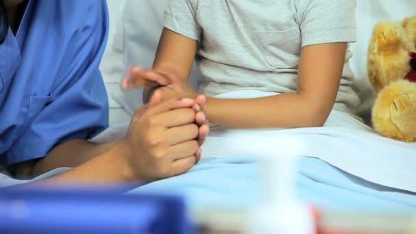 Медсестра втішає маленьку дівчинку в лікарняному ліжку — стокове відео