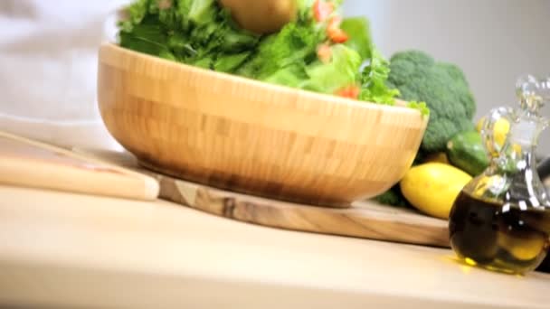 Fille sur comptoir de cuisine mélangeant feuilles de salade — Video