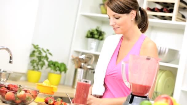 Female adding strawberries to fruit drink — Stock Video