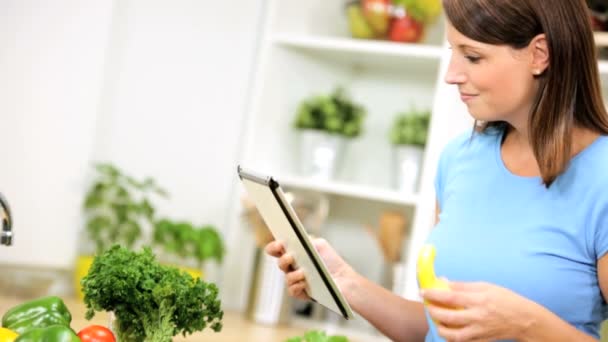 Mujer usando la tableta inalámbrica en la cocina — Vídeos de Stock