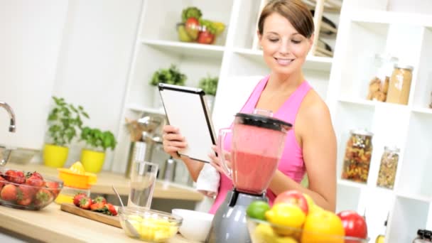 Menina usando tablet sem fio preparar smoothie fruta — Vídeo de Stock