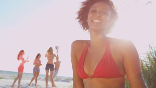 Girl sitting on beach while friends play ball — Stock Video