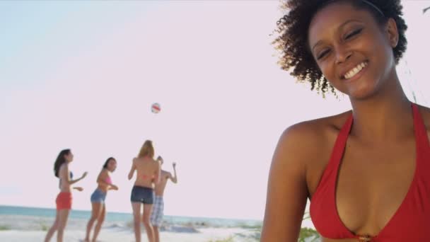 Girl sitting on beach while friends play ball — Stock Video