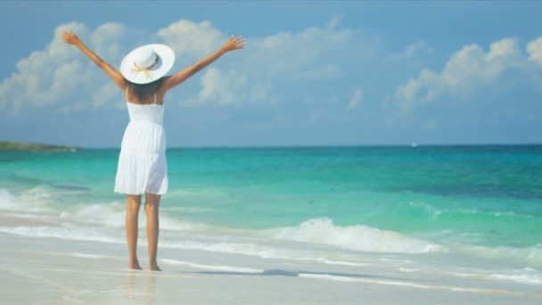 Mujer en vestido blanco y sombrero de paja al lado de un océano tropical — Vídeos de Stock