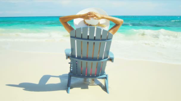 Chica en sombrero de sol sentado en silla de playa de madera — Vídeos de Stock