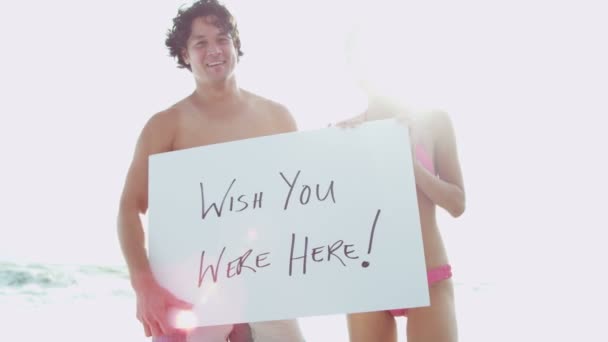 Casal na praia com placa branca — Vídeo de Stock
