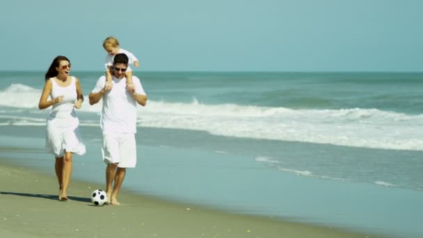 Родители с ребенком играют в футбол на пляже — стоковое видео