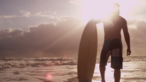 Homme tenant une planche de surf sur la plage — Video