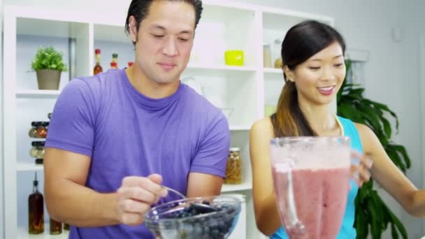 Couple putting ingredients to electric blender — Stock Video