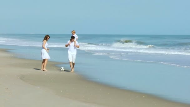 Parents with baby kicking ball on beach — Stock Video