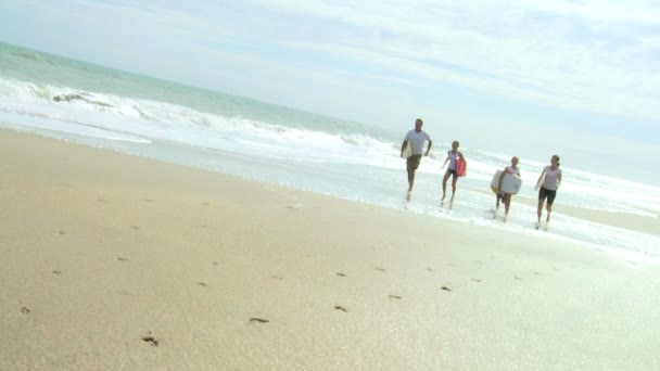 Family running with bodyboards on beach — Stock Video