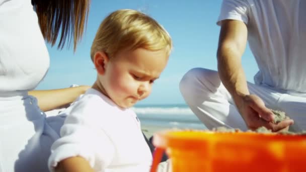 Родители с сыном играют на песчаном пляже — стоковое видео
