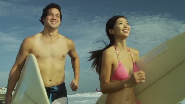 Surfing couple running beside ocean — Stock Video