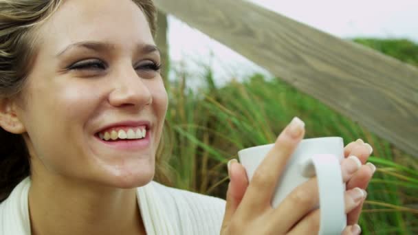 Дівчина на пляжі п'є каву — стокове відео