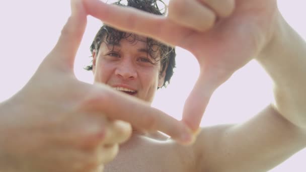 Mann am Strand macht Fingerrahmen — Stockvideo