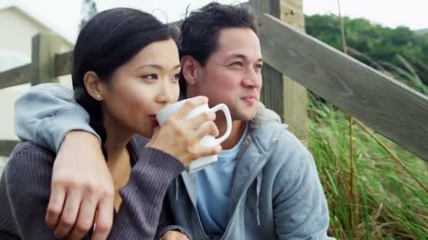 Пара на пляже пьет кофе — стоковое видео