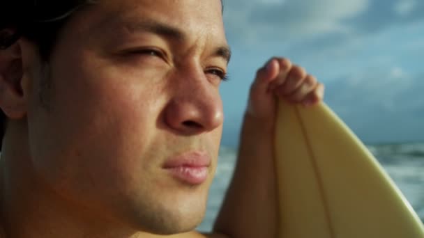 Мужчина держит доску для серфинга на пляже — стоковое видео