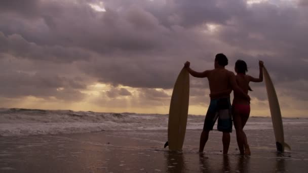 Pareja con tabla de surf en la playa — Vídeo de stock