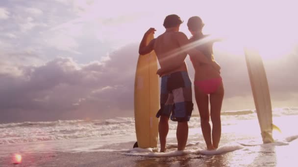 Casal ao pôr do sol assistindo ondas do oceano — Vídeo de Stock
