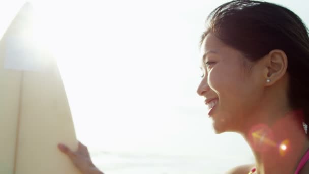 Chica sosteniendo tabla de surf en la playa — Vídeo de stock