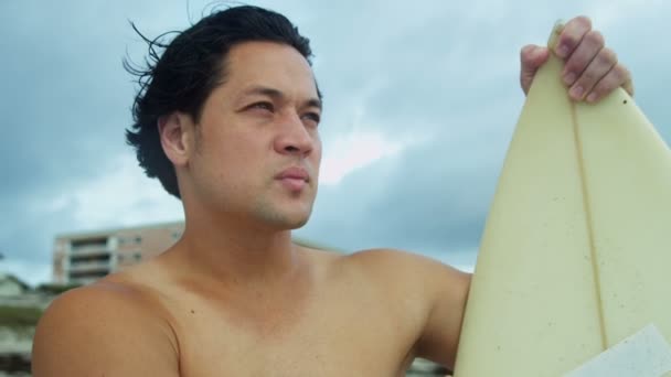 Homme avec planche de surf regardant les vagues — Video