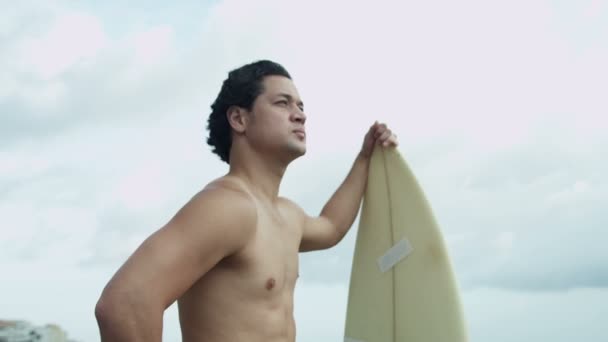 Hombre con tabla de surf viendo olas — Vídeos de Stock