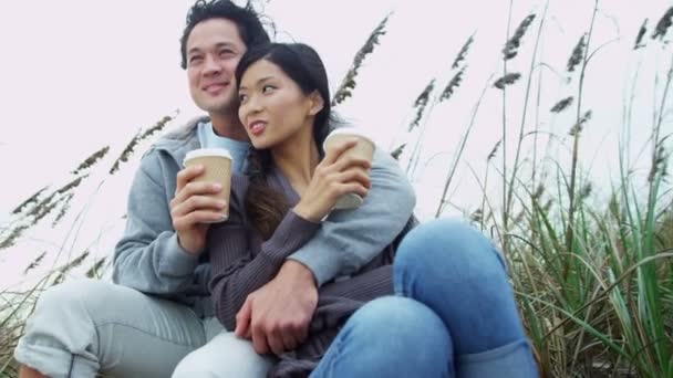 Пара отдыхающих на пляже пьет кофе — стоковое видео