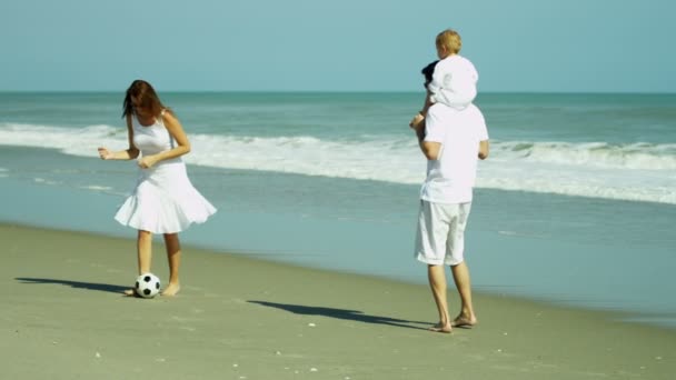Родители с ребенком играют в футбол на пляже — стоковое видео