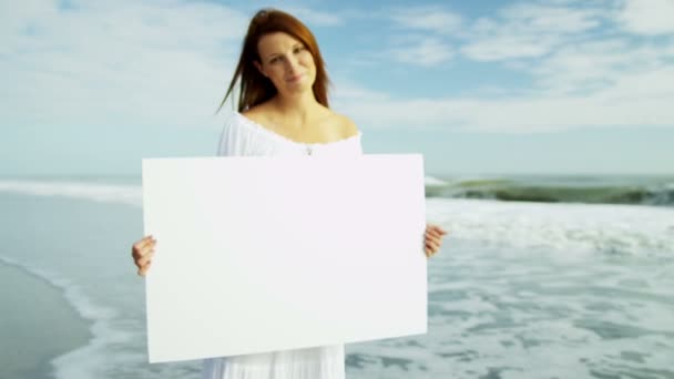 Mujer en playa sosteniendo tablero de mensajes en blanco — Vídeo de stock