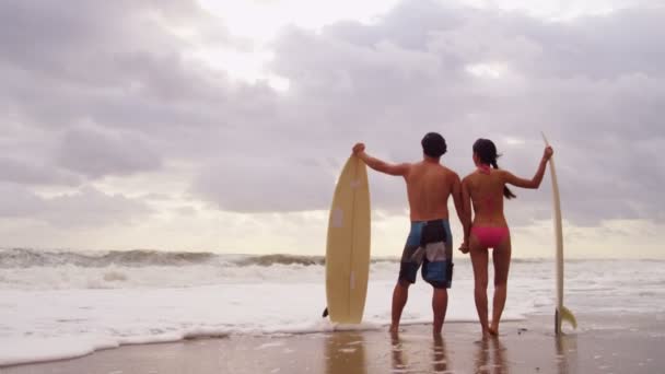 Пара з дошкою для серфінгу на пляжі — стокове відео