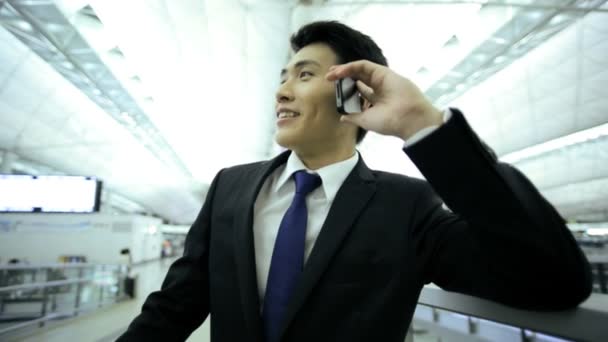 Businessman in airport talking on smartphone — Stock Video
