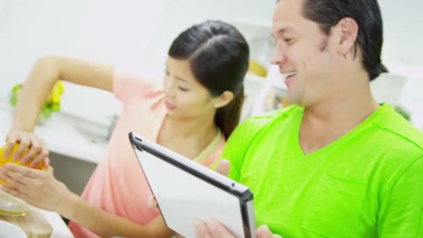 Couple using tablet and squeezing oranges — Stock Video