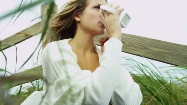Девушка на пляже пьет кофе — стоковое видео