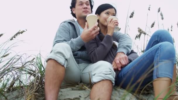 Пара отдыхающих на пляже пьет кофе — стоковое видео