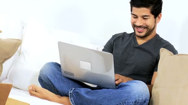 Hombre usando el ordenador portátil en sofá — Vídeos de Stock