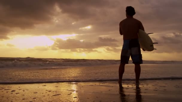 Серфер на пляже наблюдает за волнами — стоковое видео