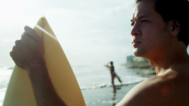 Homme tenant une planche de surf sur la plage — Video