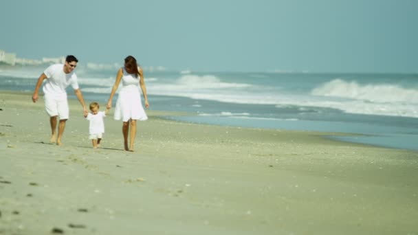 Родители с ребенком прогуливаются по пляжу — стоковое видео