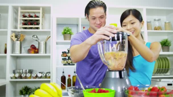 Пара положить вкусные органические фрукты в электрический блендер для свежего смузи — стоковое видео
