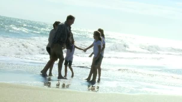 Дівчата грають з батьками на пляжі — стокове відео