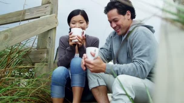 Pareja en la playa bebiendo café — Vídeos de Stock