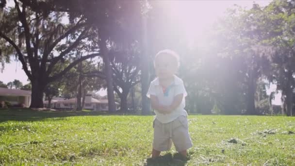 Мальчик босиком ходит по траве в парке — стоковое видео