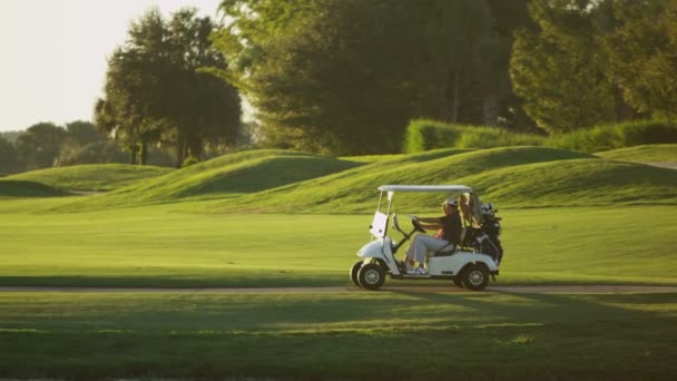 Couple de joueurs de golf conduisant chariot buggy — Video