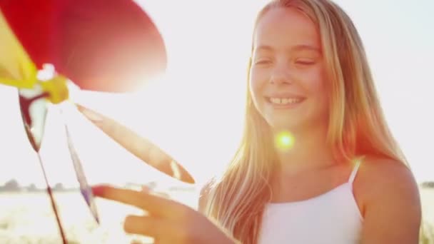 Menina ao ar livre jogando com colorido moinho de vento brinquedo — Vídeo de Stock