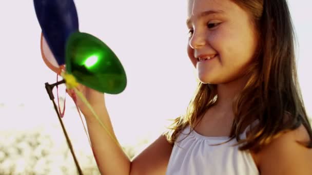 Κορίτσι που παίζουν σε εξωτερικούς χώρους με ανεμόμυλο πολύχρωμο παιχνίδι — Αρχείο Βίντεο
