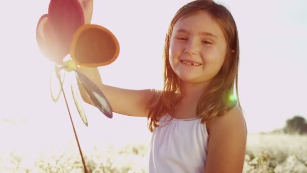 Chica al aire libre jugando con colorido molino de viento juguete — Vídeos de Stock