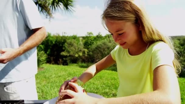 Ouders met dochter grillen van vlees van de barbecue — Stockvideo